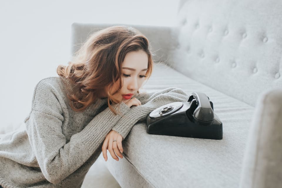 Seseorang bersandar di sofa, menatap telepon yang diam.